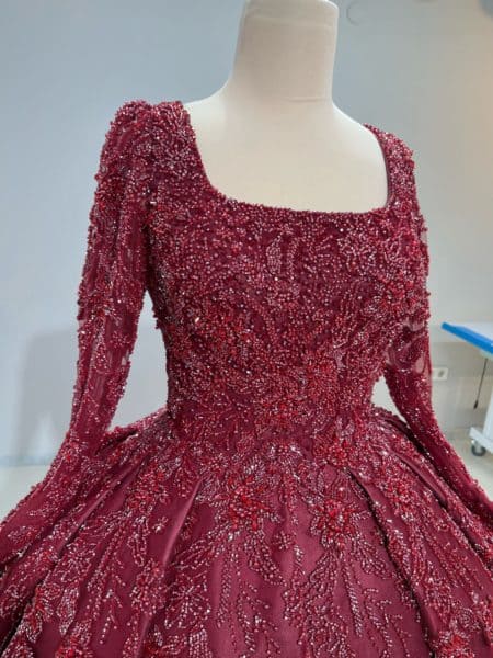 Gros plan sur le bustier et les manches longues brodées de perles et de dentelle de la robe de mariée princesse Birgul bordeaux