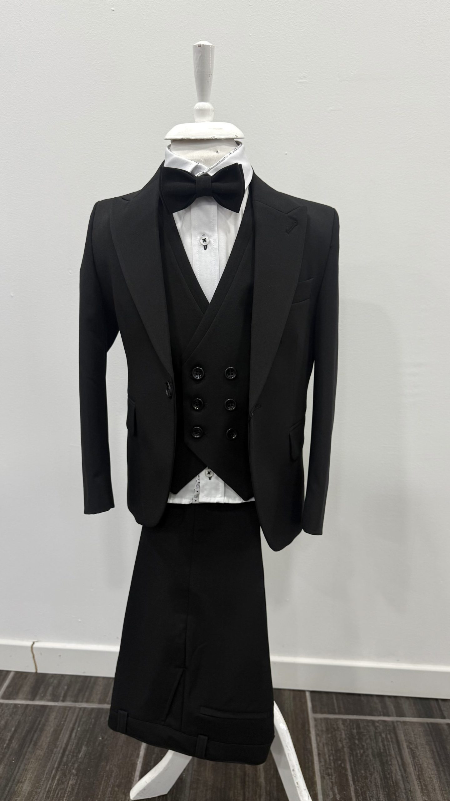 Costume de cérémonie 5 pièces noir pour garçon, présenté sur mannequin avec nœud papillon