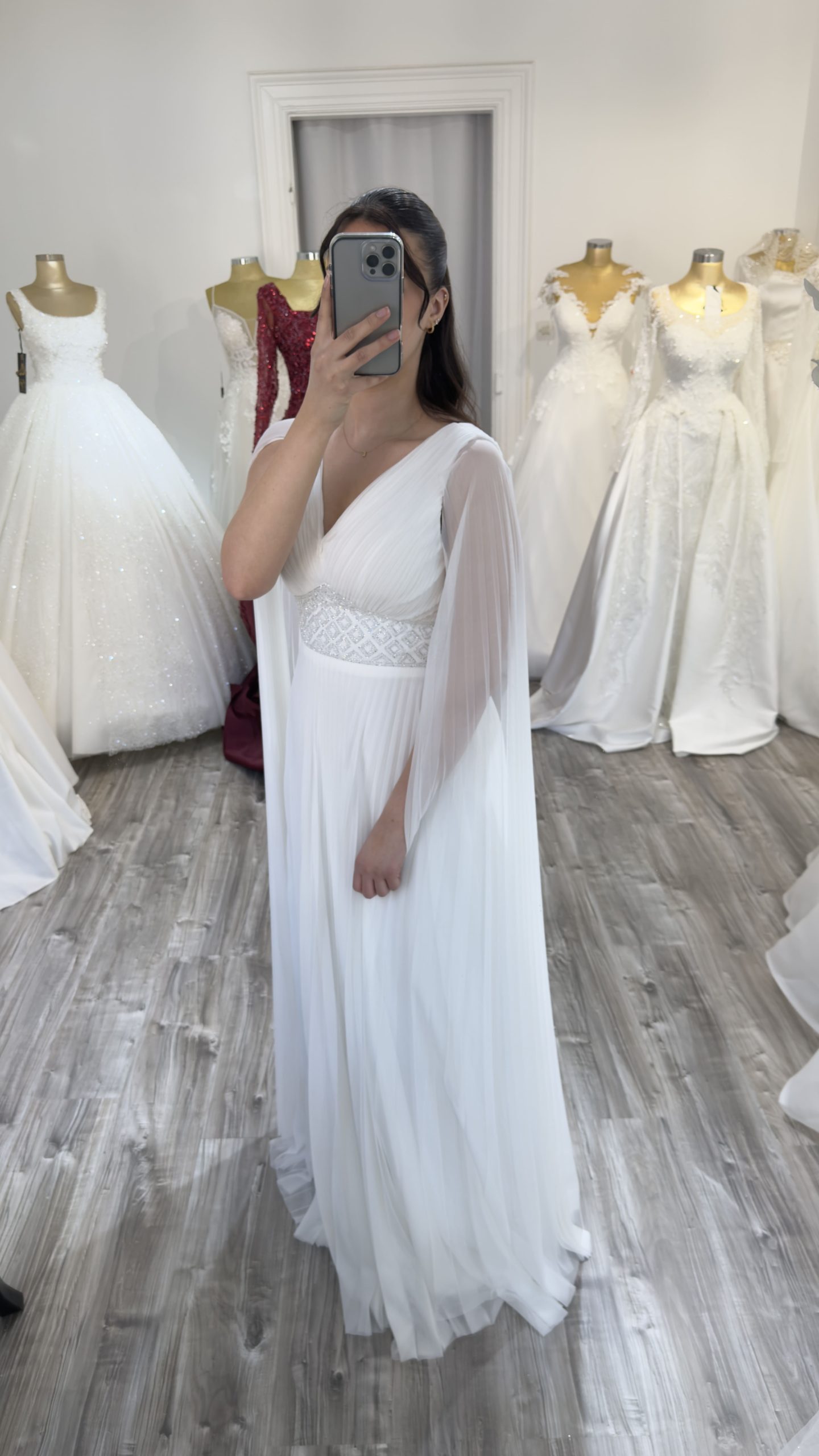 Vue de profil d'une robe de soirée blanche plissée, mise en avant des manches fluides