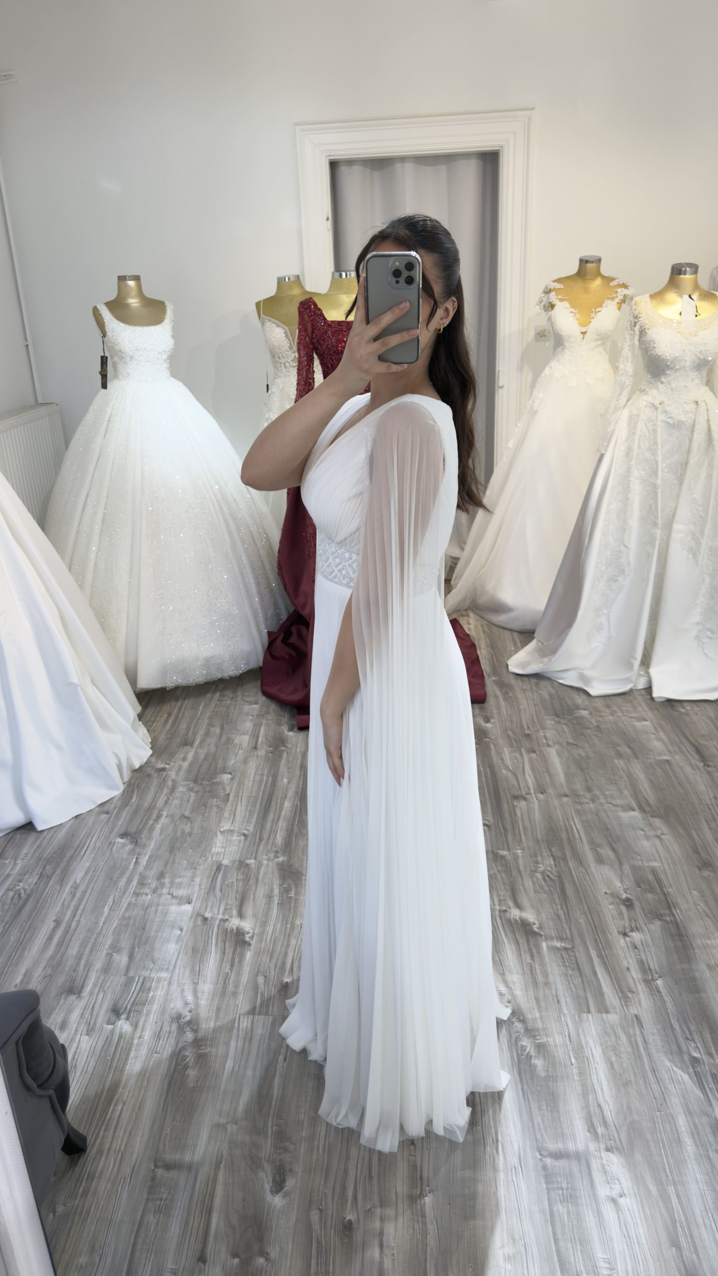 Profil d'une robe de soirée blanche plissée montrant le tombé fluide de la jupe.