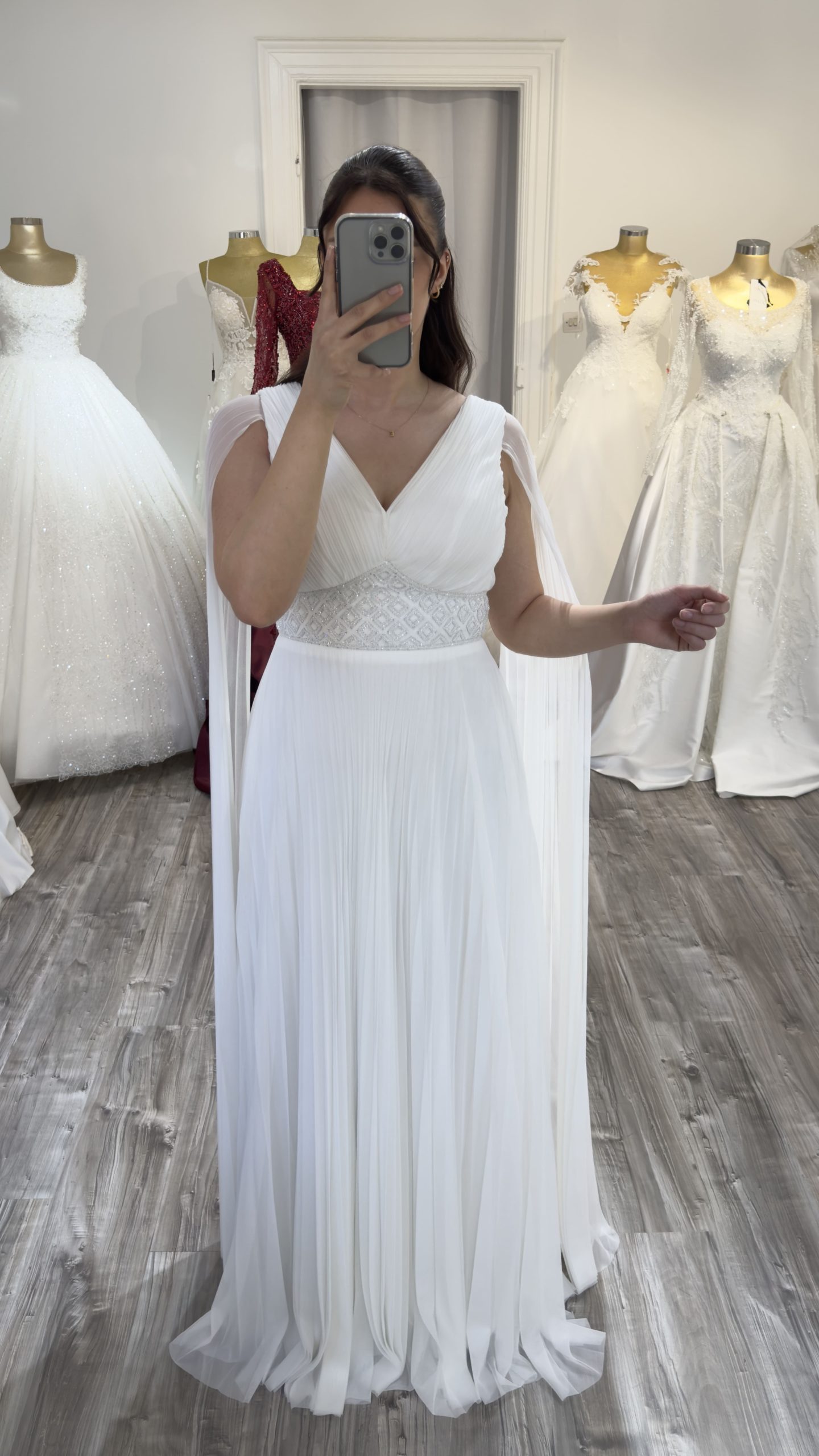 Vue de face d'une robe de soirée blanche plissée avec ceinture perlée.
