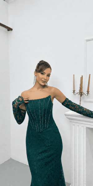 Zoom sur le buste d'une robe de soirée en dentelle vert émeraude avec détails scintillants et gants assortis