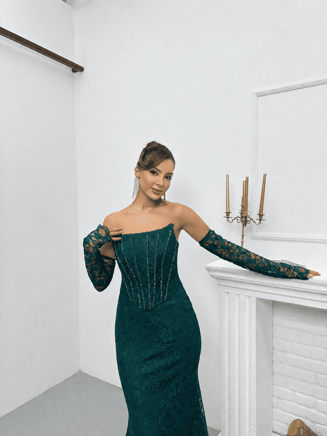 Zoom sur le buste d'une robe de soirée en dentelle vert émeraude avec détails scintillants et gants assortis