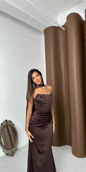 Mannequin de face portant une robe de soirée longue marron en satin avec corset structuré, détails perlés sur le bustier et foulard assorti pour Keya Mariage.